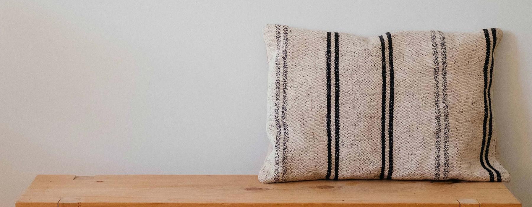 a wooden bench with a striped pillow on it